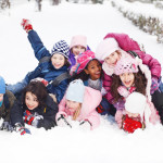 Funny group of children are lying in the snow.